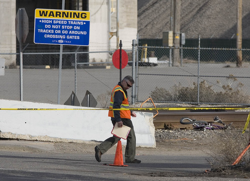 Paul Fraughton  |   Salt Lake Tribune
An investigator  looks over the area where a cyclist was struck and killed by a southbound TRAX train at 4105 South 200 West in Salt Lake City. The man's  mangled bike rests near the tracks 
 Wednesday, March 13, 2013