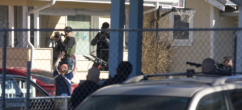 Paul Fraughton  |   Salt Lake Tribune
 With their guns trained on her, police direct a woman as she exits a house on Foulger Street between State and Main.
 Tuesday, March 19, 2013