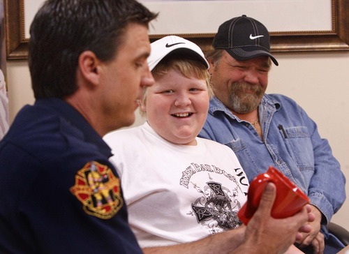 Leah Hogsten  |  The Salt Lake Tribune
Twelve-year-old C.J. Saulsgiver of Roy performed CPR on his mother to save her life on his birthday. C.J. and his father, Doc Saulsgiver, laugh as Roy Fire Department Chief Jason Poulsen presents the boy with gifts from the firehouse Friday at McKay-Dee Hospital. C.J. learned the skill only months ago through a foster care safety training course.