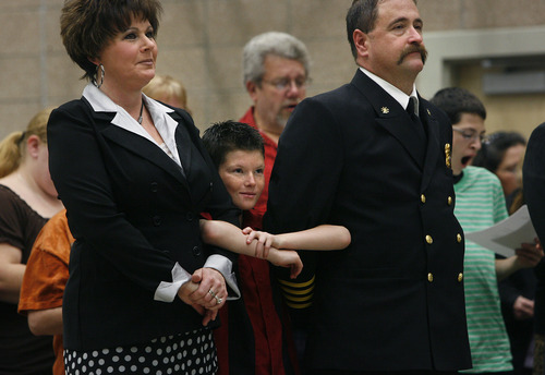 Scott Sommerdorf   |  The Salt Lake Tribune
Cyndi Becraft, left, stands with her son Daxtin, center, and her husband, Clearfield Fire Chief Mark Becraft, at Palm Sunday services at Wasatch Elementary School. The church burned Tuesday.