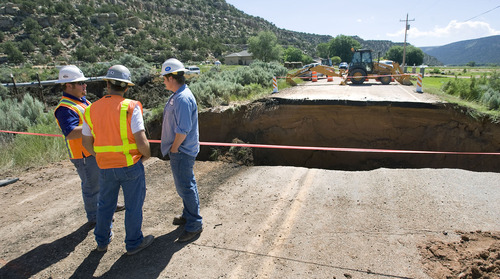 Al Hartmann  |  The Salt Lake Tribune
UDOT workers and road contractors check out a 25 foot deep 40 foot wide hole on Highway 35 about 3 miles south of Tabiona in July 2011. A sudden hail storm brought debris down a dry wash, clogging a culvert below the road and undermining the soil beneath the road causing it to wash out.
