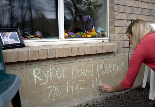 Kim Raff  |  The Salt Lake Tribune
Emily Thompson writes Ryker David Petersen's name at a memorial for the 5-month-old before family and friends gather for a candlelight vigil in American Fork on April 7, 2013. Police say Ryker was shot to death on Friday by his father, Joshua Petersen.