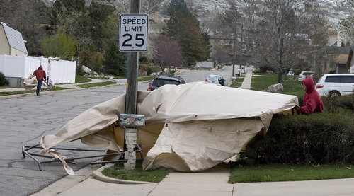 Paul Fraughton  |  The Salt Lake Tribune
Neighbors on 1100 North in Centerville remove a canvas shelter that blew from the yard behind the white fence into the street on Tuesday, April 9, 2013.