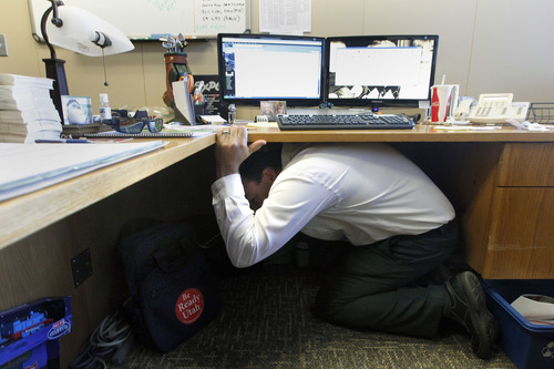 Al Hartmann  |  The Salt Lake Tribune
Ryan Longman, a manager with the State of Utah Deparment of Public Safety ducks under his desk and covers his head during the Great Utah Shake Out, an earthquake simulation excercise at the Utah State Capitol Wednesday April 17.