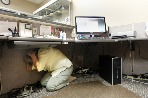 Al Hartmann  |  The Salt Lake Tribune
Judy Ainsworth a secretary with the State of Utah Deparment of Public Safety ducks under her desk and covers her head during the Great Utah Shake Out, an earthquake simulation excercise at the Utah State Capitol Wednesday April 17.
