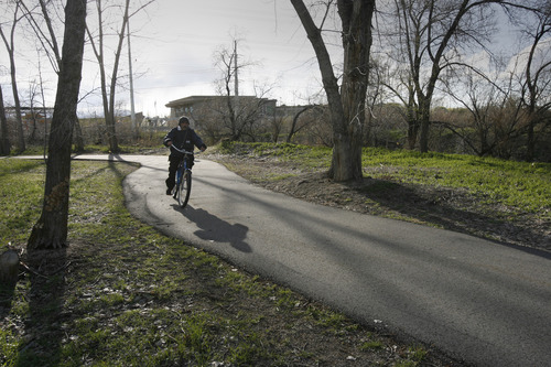 Rick Egan  | The Salt Lake Tribune 

A bicyclist rides along the Jordan River Trail east of the Utah Cultural Celebration Center at 1355 W. 3100 South. West Valley City plans to build a suspension bridge connecting the trail to the center that will commemorate the pioneers who crossed the river to settle the west side of the Salt Lake Valley.