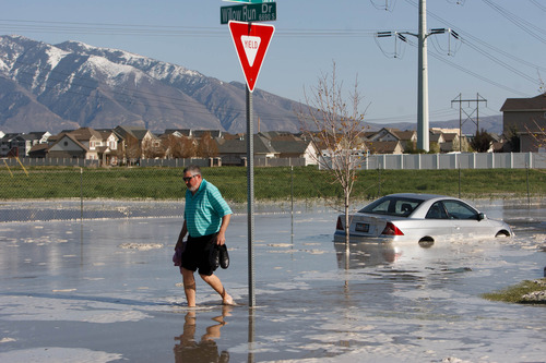 Trent Nelson  |  The Salt Lake Tribune
David Gomez makes his way across the street after a canal breach sent water flooding into a Murray neighborhood Saturday, April 27, 2013.