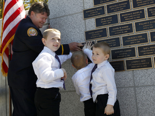 Al Hartmann  |  The Salt Lake Tribune
Clarke Christensen, of the Orem Department of Public Safety, helps hold plaque of fallen UHP Trooper Aaron Beesley while Beesley's three sons, Austin, Derek and Preston, push the plaque into place on a wall of officers who died in the line of duty at a memorial cermeony at the Utah Capitol on Thursday. Beesley died last year during a search-and-rescue operation on Mount Olympus.