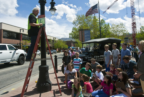 Chris Detrick  |  The Salt Lake Tribune
Duane Carling hangs a Lincoln Highway sign at the Sugarhouse Monument Tuesday May 7, 2013. Students from Hawthorne Elementary School and members of the Utah Lincoln Highway Association placed a historic Lincoln Highway marker at the Sugarhouse Monument to celebrate what was the first U.S. transcontinental highway going through the area. In the background is a 1924 Model T Touring car.