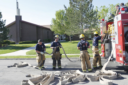 Al Hartmann  |  The Salt Lake Tribune
Unified Fire Authority firefighters roll up the hoses after responding to a fire at an LDS Church building at 7525 W. 3735 South on Monday morning May 13.