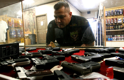 Leah Hogsten  |  Tribune file photo
Felipe Garcia looks for a Ruger .9mm in the pistol cases of Doug's Shoot 'N Sports in Taylorsville. Sales of guns in Utah spiked in December and have stayed at a high level since.