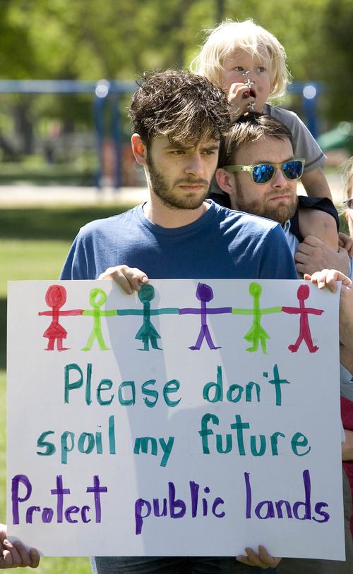 Paul Fraughton  |  The Salt Lake Tribune
Samuel Hanson holds a sign as Kevin Emerson holds his son Rowan, age 3, on his shoulders as they listen to speakers at the launch of a campaign by the group, "For Kids and Land" who  oppose two initiatives  promoted by Gov. Herbert dealing with the stewardship of public lands in Utah. The event was held at Liberty Park. Wednesday, May 22, 2013