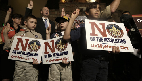 Boy Scouts from right, Joey Kalich, 10, Steven Grime, 7, and Jonathon Grime, 9, raise their hands at the close of a news conference held by people against the change in the Boy Scouts of America gay policy Wednesday, May 22, 2013, in Grapevine, Texas. Delegates to the Boys Scouts of America meeting nearby are expected to address a proposal on Thursday to allow gay scouts into the organization. (AP Photo/LM Otero)