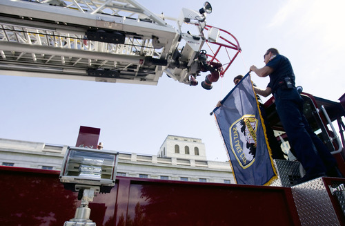 Kim Raff  |  The Salt Lake Tribune
Salt Lake City firefighers (left) Greg Holmes and Scott Campau hang a flag from the ladder of a fire engine for a memorial service for Salt Lake City firefighter Lt. Paul Hamilton, who was fatally injured 70 years ago while battling a hotel fire on a 100-foot ladder when the ladder collapsed at this spot on 400 South Main Street in Salt Lake City on June 10, 2013.