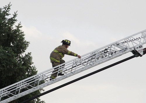 George Frey  |  Special to the Tribune
A Provo fireman climbs a ladder as a fast moving brush fire moves through a neighborhood in Provo, Utah on June 13, 2013.