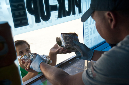 Chris Detrick  |  The Salt Lake Tribune
Tyler Smith hands a customer their order in Off the Grid's food truck parked near 200 South and 200 West Wednesday June 5, 2013.