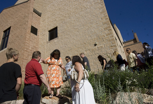 Kim Raff  |  The Salt Lake Tribune
Robin Callon is helped down a rock embankment during a procession outside of St. James the Just Catholic Church in Ogden during a Mass of Reparation ceremony on June 20, 2013.  The ceremony was scheduled to cleanse the church after James Evans was allegedly shot by his son-in-law Charles Richard Jennings Jr. during Mass on Sunday. The Rev. Erik Richtsteig led a procession around the building and sanctuary while reciting prayers to cleanse the building.