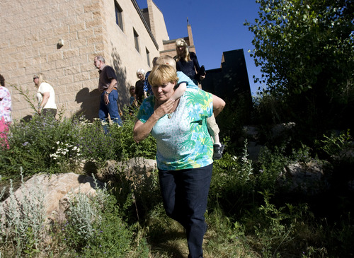 Kim Raff  |  The Salt Lake Tribune
Tara Evans helps her grandson Philip Jennings down a rock embankment during a procession outside St. James the Just Catholic Church in Ogden during a Mass of Reparation ceremony on June 20, 2013. The ceremony was scheduled to cleanse the church after James Evans was allegedly shot by his son-in-law Charles Richard Jennings Jr. during Mass on Sunday.