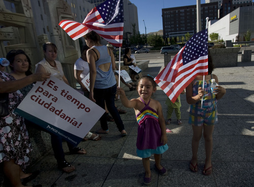 Kim Raff  |  The Salt Lake Tribune
(middle left) Kaylee Santos and (right) Jessica Vaca wave flags during the Campaign for Citizenship prayer vigil at the Wallace Bennett Federal Building in Salt Lake City on June 27, 2013. The prayer vigil comes on the heels of the U.S. Senate's passage of a immigration reform bill earlier in the day.