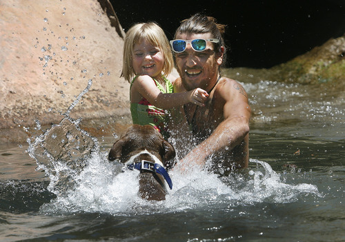 Scott Sommerdorf   |  The Salt Lake Tribune
Adam Dyet, holding his 3 year old daughter Annabelle, cools off with their dog "Cash" in the pool that "the tube" empties into in , Sunday, June 30, 2013.