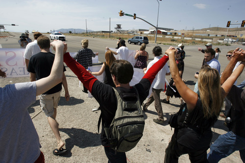 Francisco Kjolseth  |  The Salt Lake Tribune
Opponents of the NSA Data Center, in background, protest the center on the 4th of July, as they march up to the access road to the facility along Redwood Road across from Camp Williams.