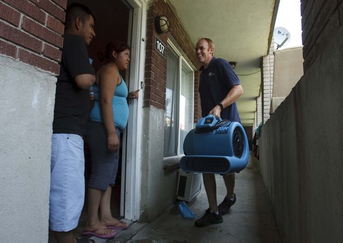 Leah Hogsten  |  The Salt Lake Tribune
Atherton Park Apartment residents Santiago Martinez and his wife Aury are greeted by Sunshine Restoration owner Russell Merrill who delivers fans to their flooded apartment. About 75 people were displaced by flooding at the Atherton Park Apartments in Taylorsville early Thursday after water backed up from storms drains and spilled into 24 basement-level apartments.