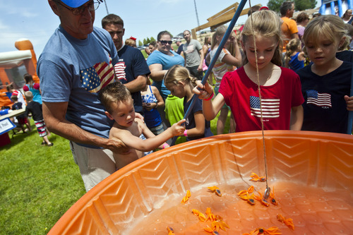 Chris Detrick  |  The Salt Lake Tribune
Larry Esplin helps his grandson Blake Richey, 3, catch a magnetic fish during the 4th of July carnival in Moroni Thursday July 4, 2013.