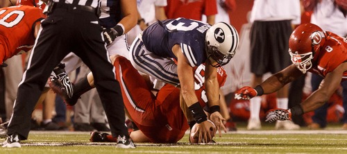 Trent Nelson  |  The Salt Lake Tribune
Brigham Young quarterback Riley Nelson (13) recovers his fumble as he's sacked by Utah defensive end Joe Kruger (99) as Utah hosts BYU college football in Salt Lake City, Utah, Saturday, September 15, 2012. Utah defensive end Nate Fakahafua (8) at right.