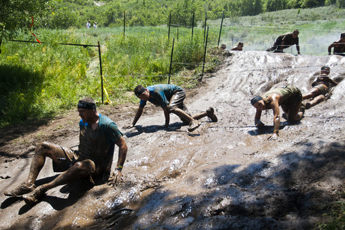 Chris Detrick  |  The Salt Lake Tribune
Competitors slide down a mud hill under barbed-wire during the Utah Spartan Beast Race at Soldier Hollow Saturday June 29, 2013. The 12-mile race included obstacles like mud pits with barbed wire, rope climbs, jumping over fire and climbing an eight-foot wall.
