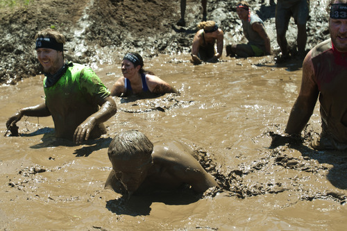 Chris Detrick  |  The Salt Lake Tribune
Competitors slide down a mud hill under barbed-wire into a mud pit during the Utah Spartan Beast Race at Soldier Hollow Saturday June 29, 2013. The 12-mile race included obstacles like mud pits with barbed wire, rope climbs, jumping over fire and climbing an eight-foot wall.