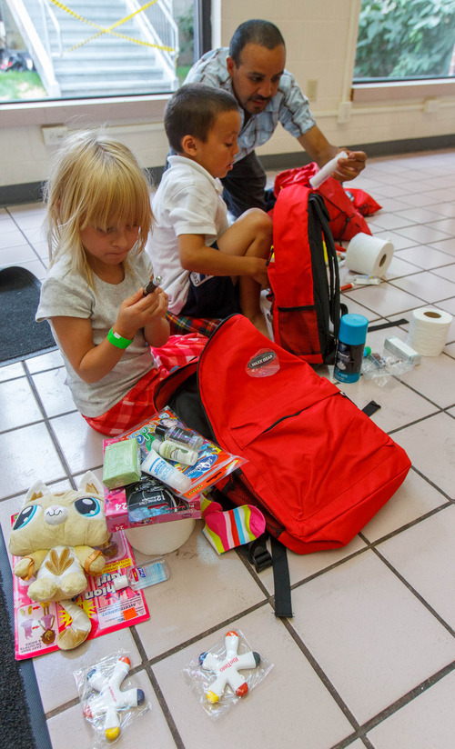 Trent Nelson  |  The Salt Lake Tribune
Paige Stanley, Andrew Bartholomew and Patrick Bartholomew look through the items in backpacks they were given as the Salt Lake Board of Realtors held its annual Christmas in July event at The Road Home homeless shelter in Salt Lake City on Friday, July 12, 2013.