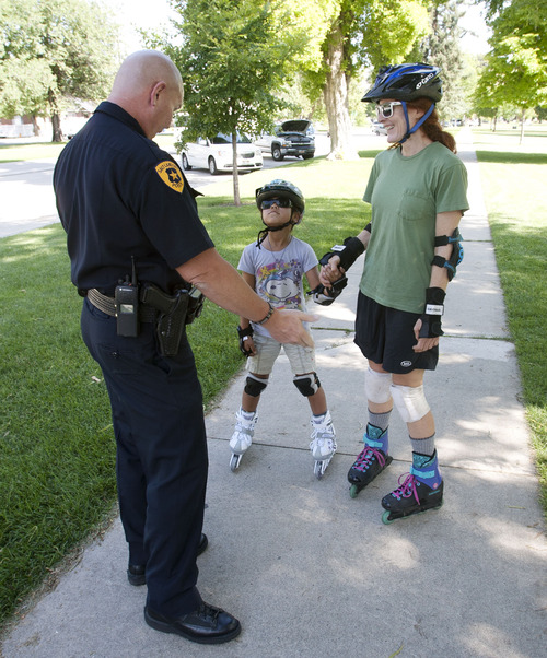 Steve Griffin | The Salt Lake Tribune
Salt Lake City police Detective Rick Wall stops nine year-old Mei Curry and her friend, Anne Yeagle, to give them a ticket for playing safe by wearing helmets and following traffic rules as they inline skate around Liberty Park in Salt Lake City, Utah Monday July 15, 2013. The ticket Wall gave the pair is good for a 6-inch sandwich at Subway. SLCPD and other Utah law enforcement agencies will be give children the tickets for being safe throughout the summer. It was Curry's birthday and she was trying out her new skates for the first time.