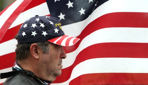 Rick Egan  |  The Salt Lake Tribune 
Stephen Meyer, with the Patriot Guard Riders, holds a flag at the benefit picnic at Cedar City Park on Main Street, Saturday, July 20, 2013. The event is to honor and raise money for Joe Thurston, a Cedar City native and Hotshot firefighter who died in the Arizona wildfire last month.