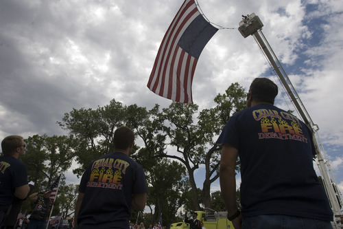 Rick Egan  |  The Salt Lake Tribune
Members of the Cedar City Fire Department stand at attention as a giant flag is raised at the corner of 100 East and 200 South, at the benefit picnic at Cedar City Park on Main Street, Saturday, July 20, 2013. The event is to honor and raise money for Joe Thurston, a Cedar City firefighter who died in the Arizona wildfire last month.