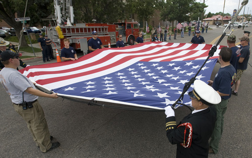 Rick Egan  |  The Salt Lake Tribune 
Members of the Cedar City Fire Department help raise a giant flag at the corner of 100 East and 200 South, at the benefit picnic at Cedar City Park on Main Street, Saturday, July 20, 2013. The event is to honor and raise money for Joe Thurston, a Cedar City native and Hotshot firefighter who died in the Arizona wildfire last month.