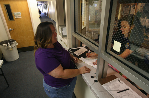 Scott Sommerdorf   |  The Salt Lake Tribune
Inmate Kristell Thomas, left, deposits her check via the staff at the Orange Street Community Correctional Center in Salt Lake City, Thursday, July 18, 2013. The Utah State Prison's female inmate population has surpassed capacity frequently between January and July of this year. Administrators at Orange Street are trying to address that problem.