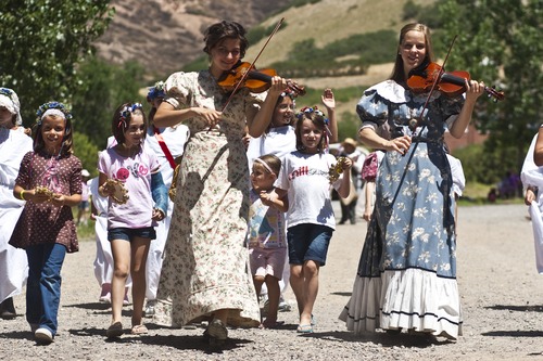 Chris Detrick | The Salt Lake Tribune 
Violinists Phoebe Romney and Mary-Martha Jackson participate in the Village Parade walk during the 2011 Pioneer Days Festival at This Is the Place Heritage Park.