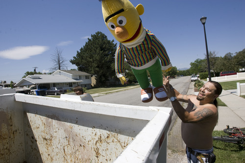 Rick Egan  | The Salt Lake Tribune 

Victor Aguirre chucks a giant Bert doll into the garbage bin in front of his house in Taylorsville, Friday, July 26, 2013. Taylorsville placed large garbage bins in each neighborhood for a day as part of the annual cleanup program.