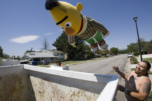 Rick Egan  |  The Salt Lake Tribune
Victor Aguirre chucks a giant Bert doll into the garbage bin in front of his house in Taylorsville on Friday. Taylorsville placed large garbage bins in each neighborhood for a day as part of the annual cleanup program.