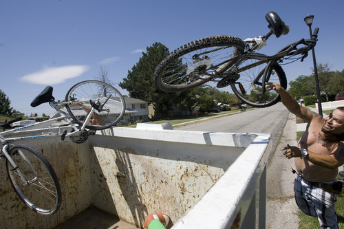 Rick Egan  | The Salt Lake Tribune 

Dakoda and Victor Aguirre toss bicycles into the garbage bin in front of their house in Taylorsville, Friday, July 26, 2013. Taylorsville placed large garbage bins in each neighborhood for a day as part of the annual cleanup program.
