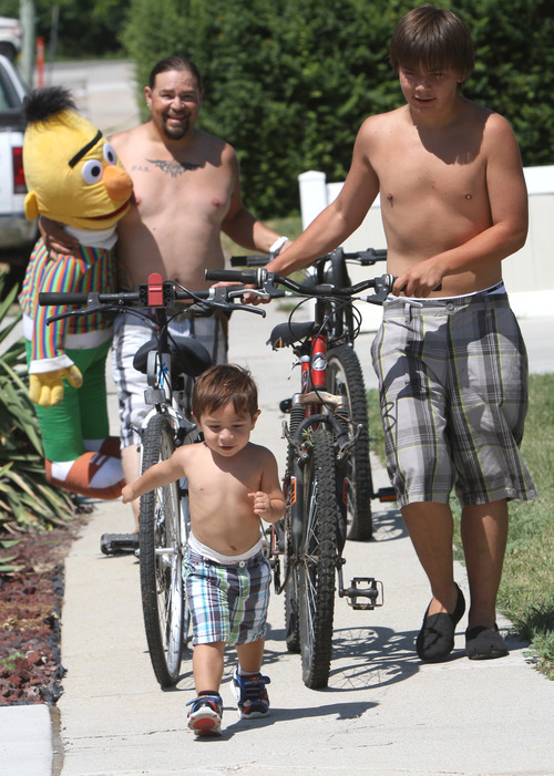 Rick Egan  | The Salt Lake Tribune 

Dakoda and Kruz with their father Victor Aguirre bring Bert, and some extra bicycles to toss into the garbage bin near their house in Taylorsville, Friday, July 26, 2013. Taylorsville placed large garbage bins in each neighborhood for a day as part of the annual cleanup program.