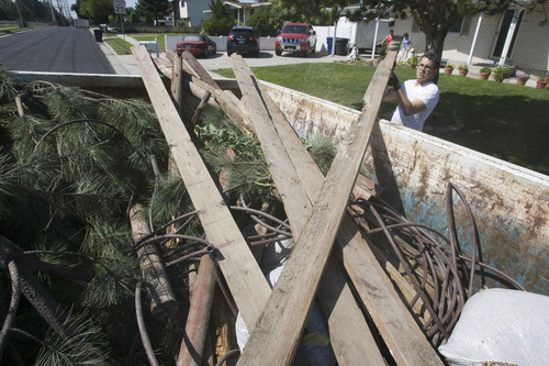 Rick Egan  | The Salt Lake Tribune 

Josh Alvarez lifts pieces of lumber into the garbage bin in front of his house in Taylorsville, Friday, July 26, 2013. Taylorsville placed large garbage bins in each neighborhood for a day as part of the annual cleanup program.