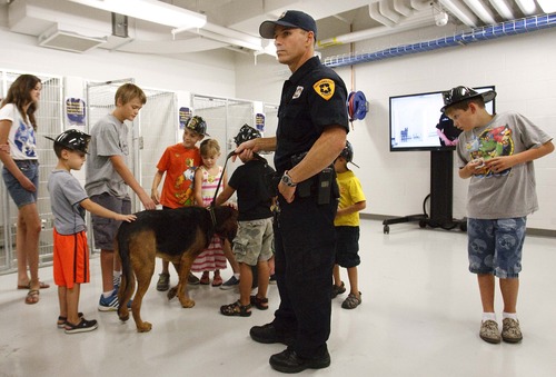 Leah Hogsten  |  The Salt Lake Tribune
Salt Lake Police K-9 handler Mike Serio and his 4-year-old Bloodhound "Junior" educate visitors at the new Public Safety Building on the job descriptions of the seven dogs the police department uses Friday, July 26, 2013. "Bloodhound in Blue: The True Tales of Police Dog JJ and His Two-Legged Partner" by author Adam David Russ chronicles the adventures of Salt Lake Police K-9 handler Mike Serio and his former police bloodhound JJ, who helped catch 271 criminals in his career, even as he battled cancer.