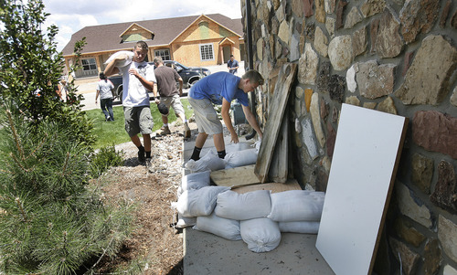 Scott Sommerdorf   |  The Salt Lake Tribune
Volunteers from the Cedar City 11th Ward drop sandbags around a home that has a basement that flooded in the Equestrian Pointe neighborhood of west Cedar City, Sunday, July 28, 2013.