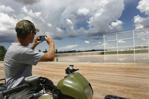 Scott Sommerdorf  |  The Salt Lake Tribune
Eric Baler stops to make a photo of the flooded baseball field in the Equestrian Pointe neighborhood of west Cedar City, Sunday, July 28, 2013.