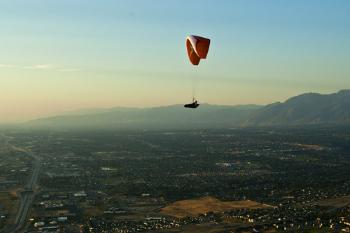 Chris Detrick  |  The Salt Lake Tribune
With pollution visible in the background, a paraglider flies over Point of the Mountain Flight Park at Steep Mountain near Geneva Rock Products in Draper Friday July 19, 2013.