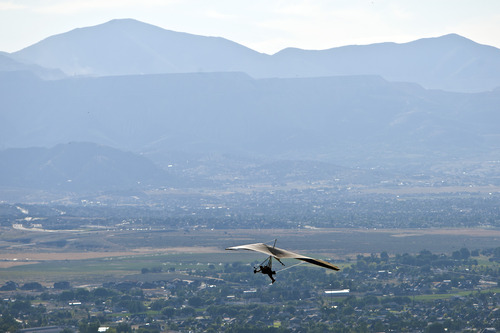 Chris Detrick  |  The Salt Lake Tribune
With pollution visible in the background, a hang glider flies over Point of the Mountain Flight Park at Steep Mountain near Geneva Rock Products in Draper Friday July 19, 2013.