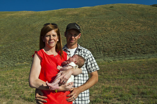 Chris Detrick  |  The Salt Lake Tribune
With Steep Mountain in the background, Desiree Voight, Ryan Voight and their baby Scarlett pose for a portrait at Point of the Mountain Flight Park near Geneva Rock Products in Draper Friday July 19, 2013.