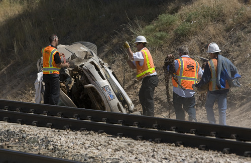 Rick Egan  | The Salt Lake Tribune 

FrontRunner officials check out a car that was hit by the train this morning, killing the driver, on 4800 South 2700 West in Roy, Friday, August 2, 2013.