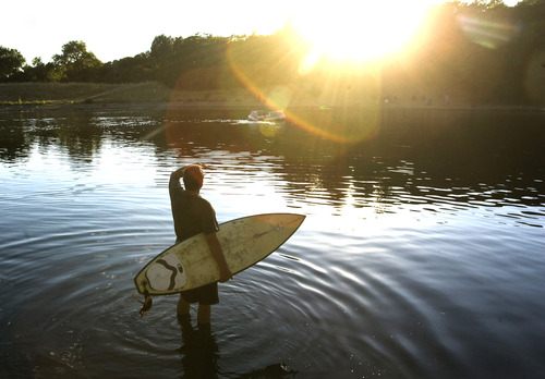 Rick Egan  | The Salt Lake Tribune 

Ray Walker cools off in Farmington Pond with his surfboard,  Wednesday, July 31, 2013. Walker grew up in Hawaii.